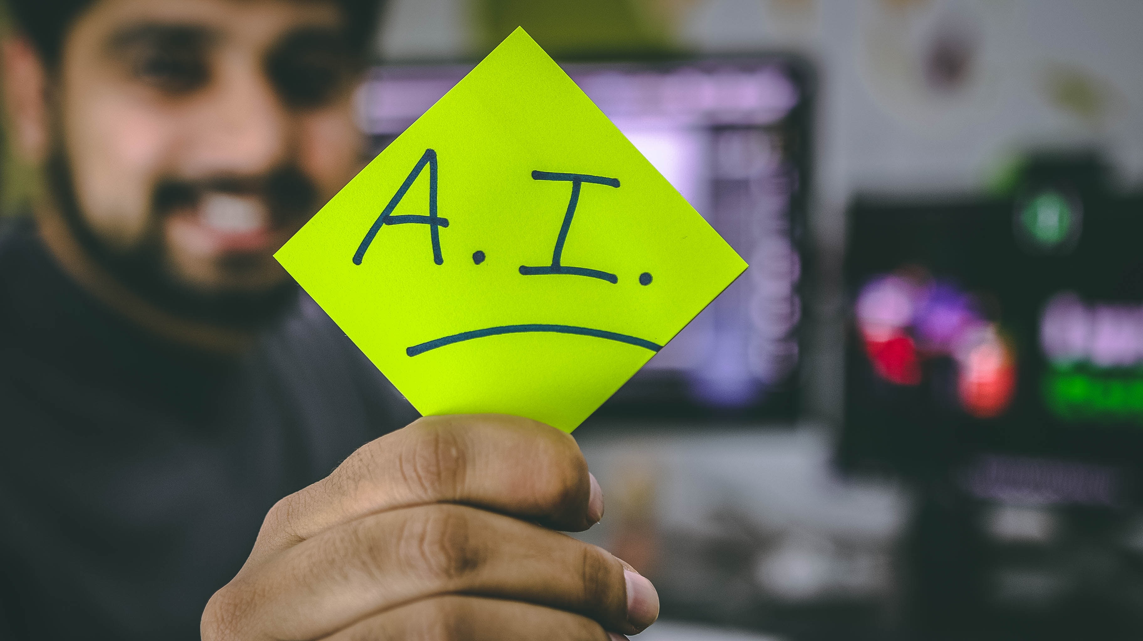 Une personne tenant un post-it sur lequel est écrit A.I.