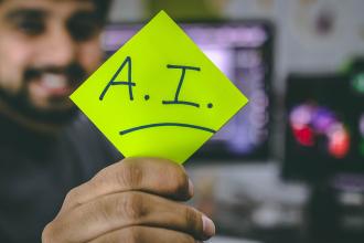 Une personne tenant un post-it sur lequel est écrit A.I.